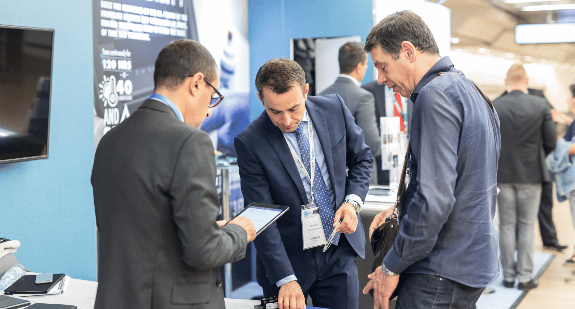 three men talking at a trade show booth